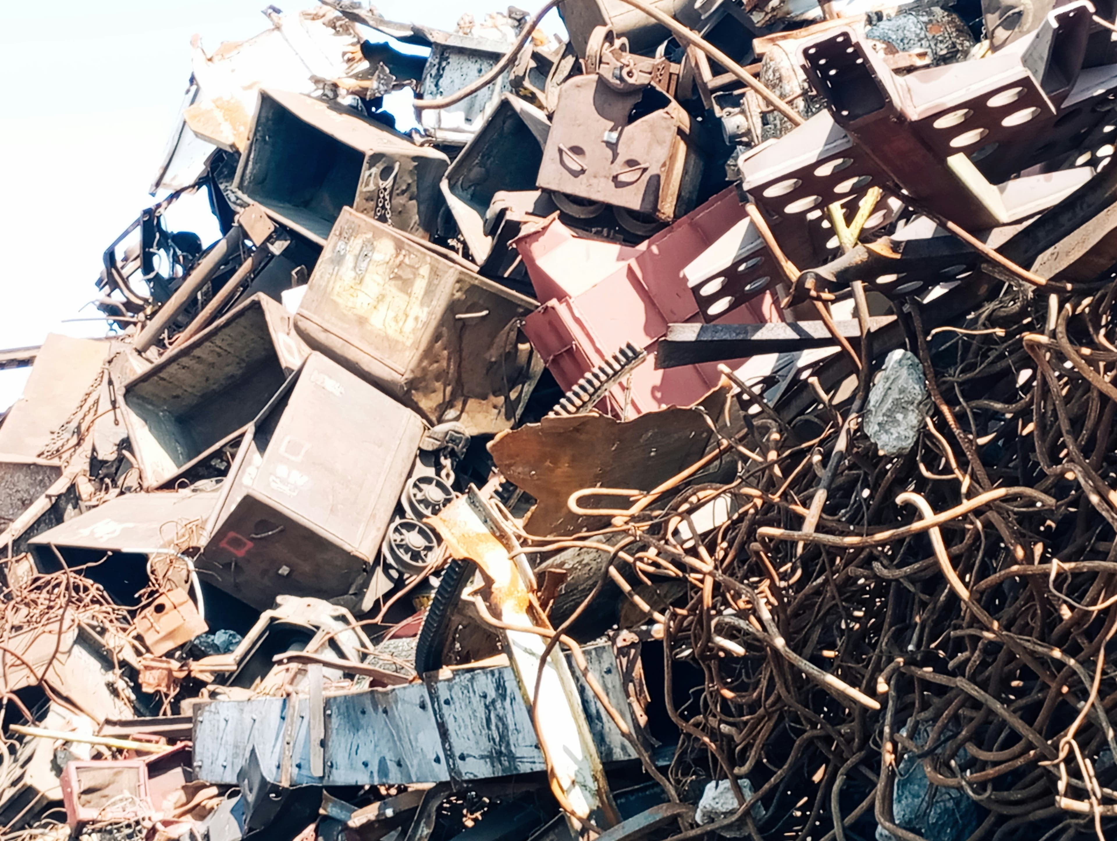 Scrap steel sections and tangled copper wire piled in a metal recycling yard
