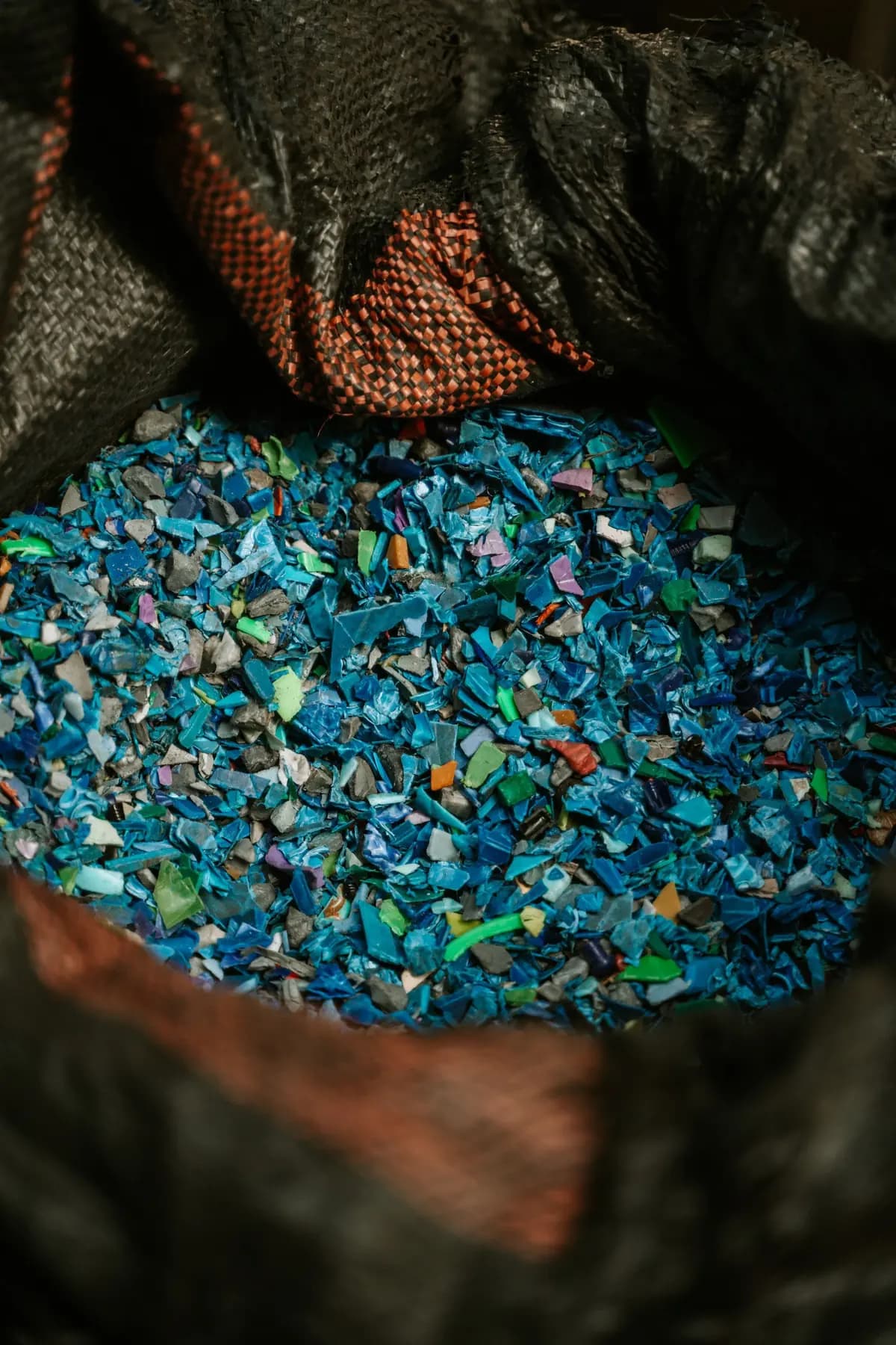 Shredded blue and green plastic flakes in an open sack