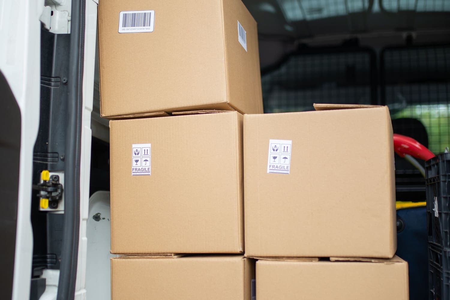Cardboard cartons stacked in the open back of a white van, ready for collection